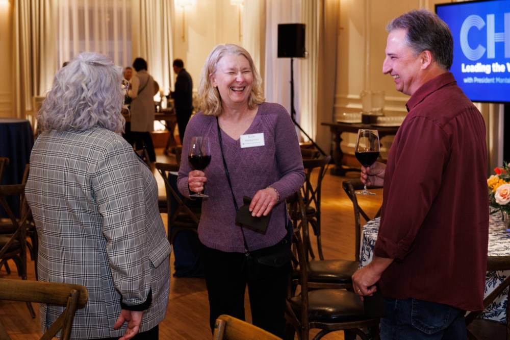 Alumni laugh while speaking with Susan Proctor